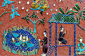 Wat Xieng Thong temple in Luang Prabang, Laos.  La Chapelle Rouge , the Red Chapel. The exterior walls are decorated with colourful mosaics on a pink background with scenes of people daily activities. South wall. 